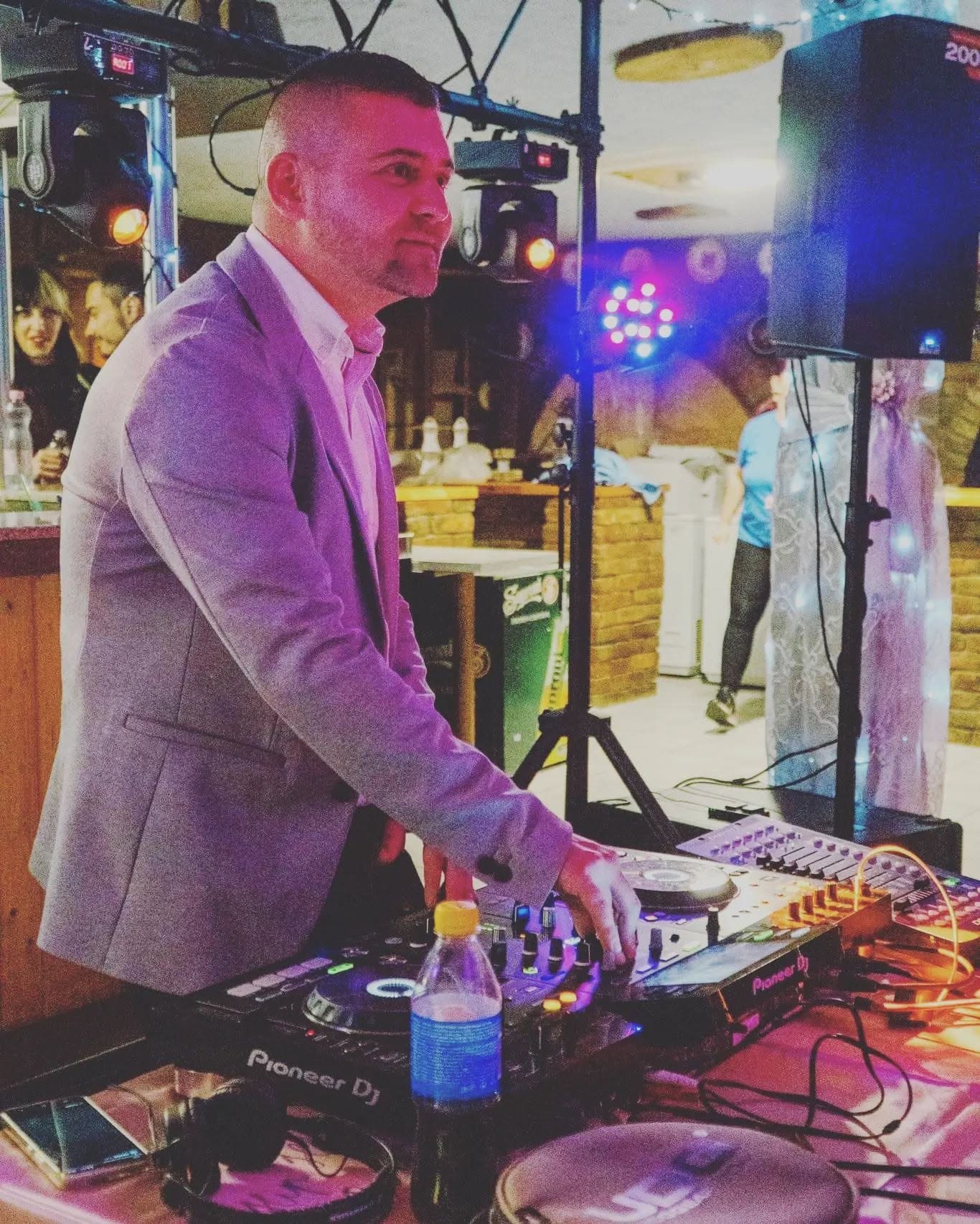 DJ Sisák Zolee a Pioneer DJ-pultnál, színes fények között