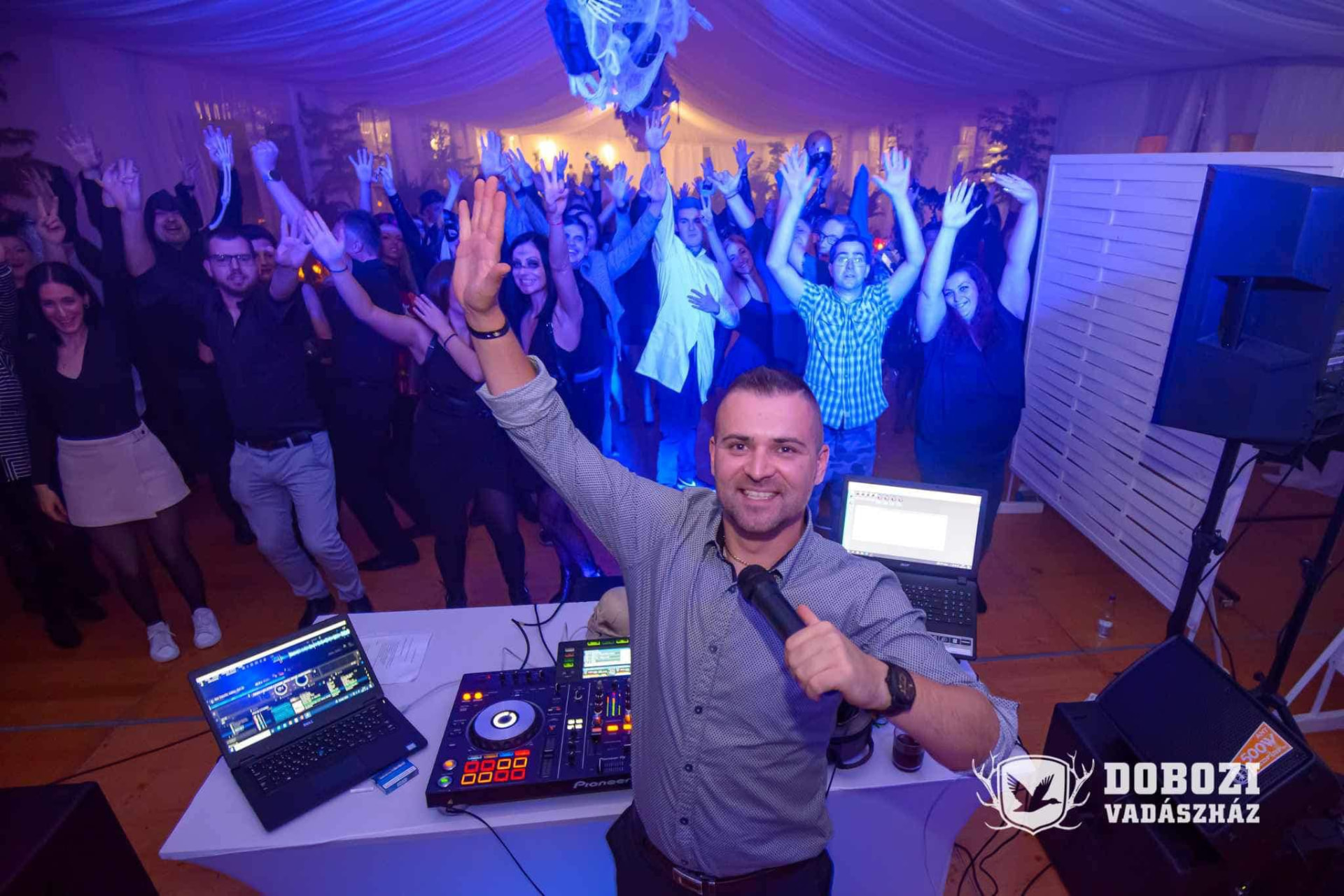 DJ Sisák Zolee a pult mögött, bulizó közönséggel